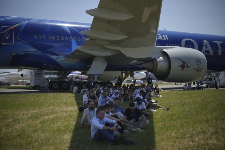 Visitors sit in the shade of a Boeing airliner&#8217;s wing at the Paris Air Show on Wednesday in Le Bourget, north of Paris.  (Thibault Camus / The Associated Press)