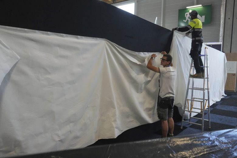 Workers put a white canvas over a black wall that blocks the Israeli pavilions and that has been erected at the Paris Air Show on Monday. (Michel Euler / The Associated Press)