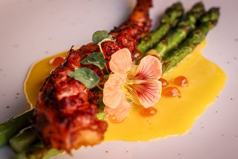 The smoked octopus at 84 Yesler features grilled asparagus, hollandaise, ikura and nasturtium. (Kevin Clark / The Seattle Times)