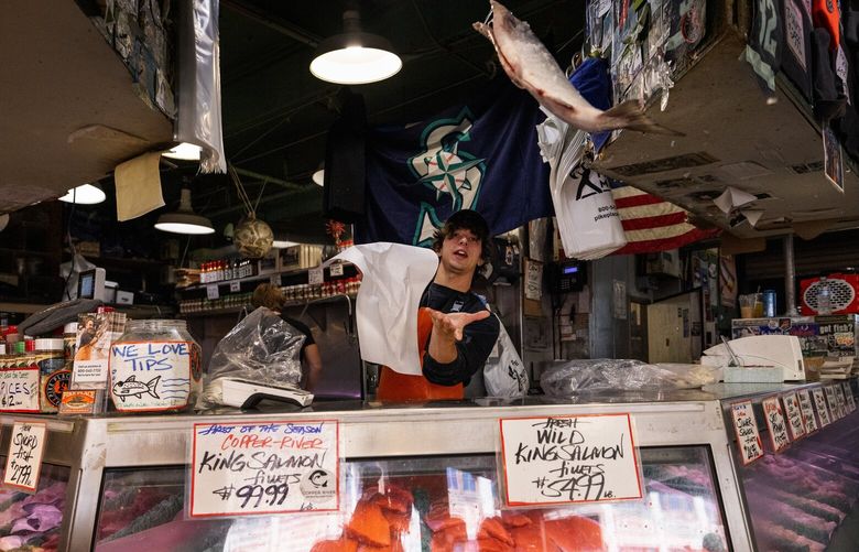Pike Place Fish Market’s fishmonger Kobi Bynum catches a Copper River Sockeye Salmon for a customer, Monday, June 16, 2025, in Seattle.