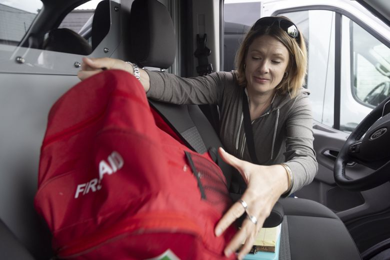 April Coberly, a case manager with Sound Behavioral Health, loads a first aid kit and supplies into a mobile crisis team van at the organization’s office in Auburn last month. (Akash Pamarthy / The Seattle Times)