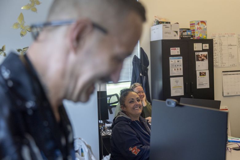 Certified peer counselor Daniel Ramirez, left, and case manager Sara Pearson, center, members of Sound Behavioral Health’s mobile crisis team, share a laugh at the organization’s office in Auburn. The team is part of King County’s expanding mental health crisis response system, which responds to behavioral health emergencies without police when there is no immediate safety risk. (Akash Pamarthy / The Seattle Times)