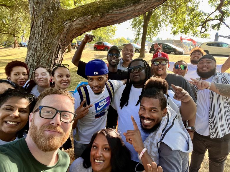 Colin Pierce, bottom left, original coordinator for the International Baccalaureate at Rainier Beach High School, takes a selfie with his former students, 10 years after graduation. Former Principal Dwane Chappelle, now director of Seattle’s Department of Education and Early Learning, stands in the background.  (Colin Pierce)