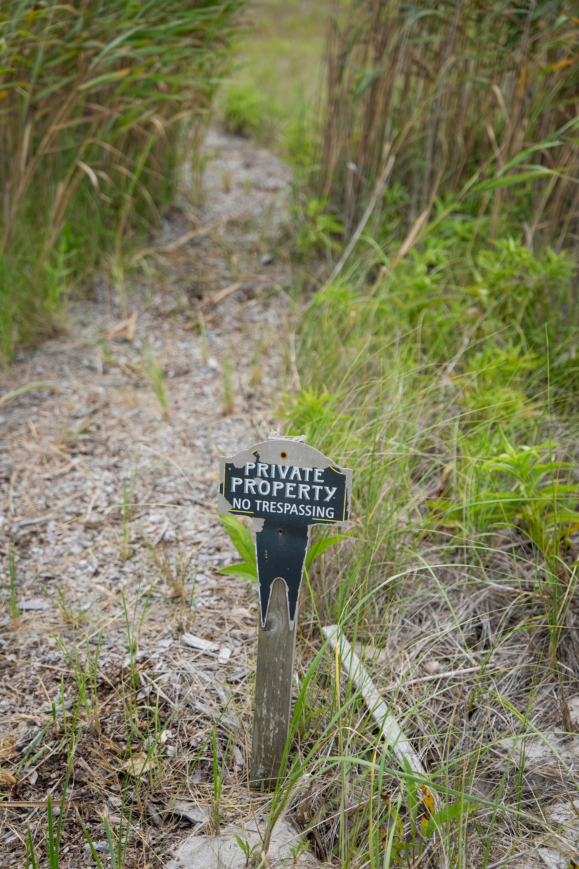 A private property sign on a pathway to Moriches Bay in Westhampton Beach, N.Y. Tucked among exclusive real estate, a family’s 18-foot-wide strip of land is not just an oceanside parking spot, it’s their legacy. (Vincent Alban/The New York Times)