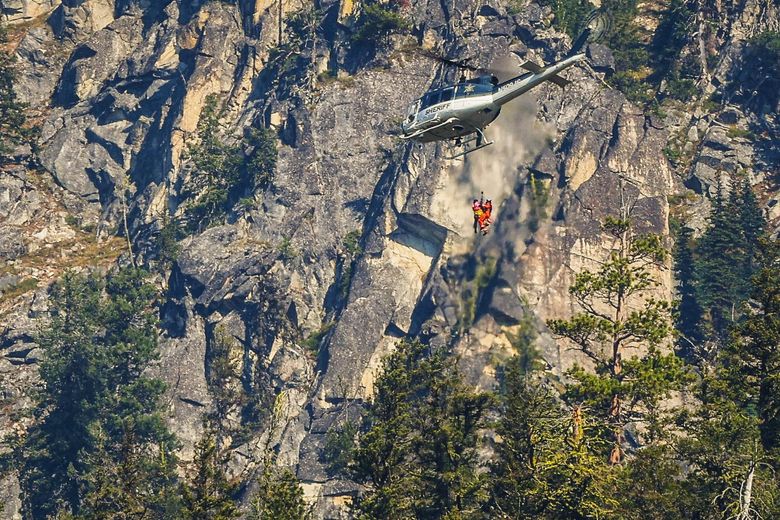 Authorities rappel from a Spokane County sheriff’s helicopter near Leavenworth on Friday to the site where human remains believed to be Travis Decker’s were found near Grindstone Mountain. (Nick Wagner / The Seattle Times)