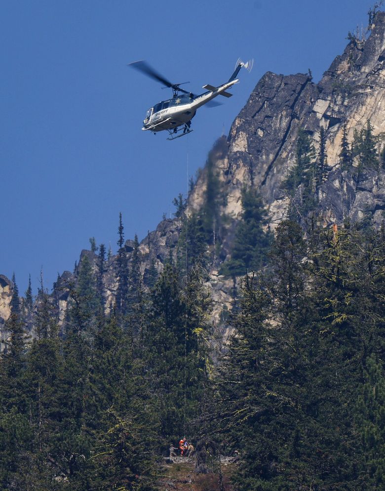 Authorities rappel from a Spokane County sheriff’s helicopter near Leavenworth on Friday to the site where human remains believed to be Travis Decker’s were found Thursday near Grindstone Mountain. (Nick Wagner / The Seattle Times)