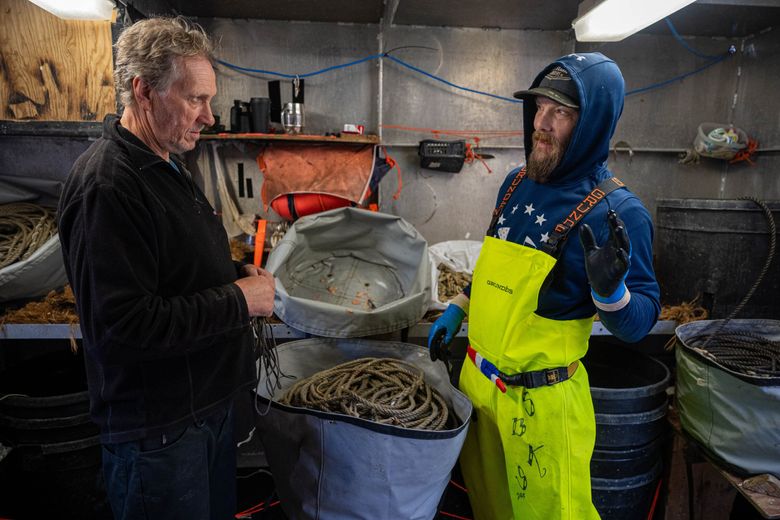 Omar Sørvik, left, talks with crew member Steve Legino in the bait shed aboard the Oracle in Dutch Harbor in May. Sørvik is the inventor of the Sago Solutions capsule, which is designed to protect a longline catch from hungry whales, and was tested aboard the Oracle. (Loren Holmes / Anchorage Daily News)
