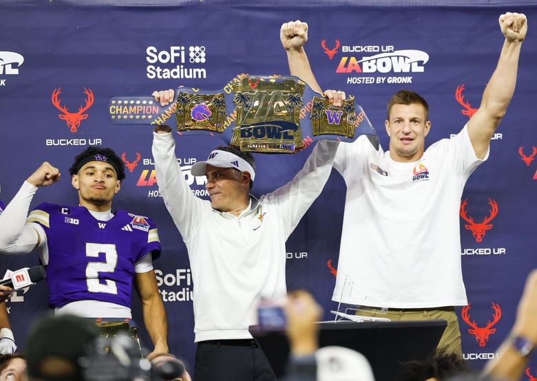 From left, quarterback Demond Williams Jr., coach Jedd Fisch and Rob Gronkowski raise their arms after the Washington Huskies’ win against the Boise State Broncos in the Bucked Up LA Bowl, hosted by Gronk, on Saturday at SoFi Stadium in Inglewood, Calif. (Dean Rutz / The Seattle Times)