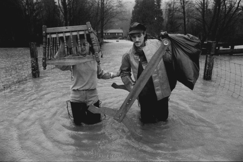 Suzanne and Flip Balou wade through the knee-deep water covering their driveway as they evacuate their home on the north bank of the Skagit River in Hamilton in 1989. (Barry Wong / Seattle Times)