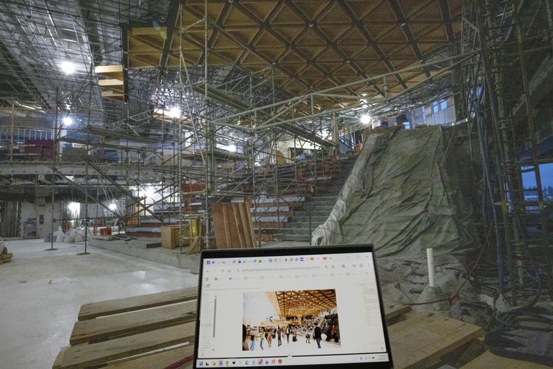 While scaffolds fill Concourse C, an artist’s rendering shows what the expansion will look like when it opens in the spring. The stepped area is designed to be a meeting place, which officials are calling the “Tree at C.” (Ellen M. Banner / The Seattle Times)
