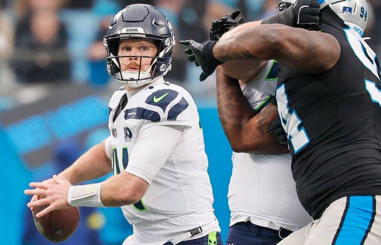 O quarterback do Seattle Seahawks, Sam Darnold, lança um passe durante o primeiro quarto no domingo, 28 de dezembro de 2025, em Charlotte, Carolina do Norte. 232074