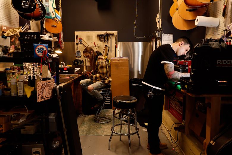 Repair tech Calvin Burns, left, and co-owner Geoff Joynes work in the backroom at Re-Animated Music as they repair guitars. (Jennifer Buchanan / The Seattle Times)