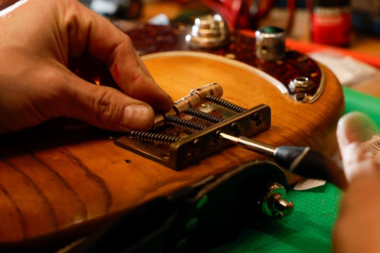 Co-owner Geoff Joynes repairs a guitar at Re-Animated Music. (Jennifer Buchanan / The Seattle Times)
