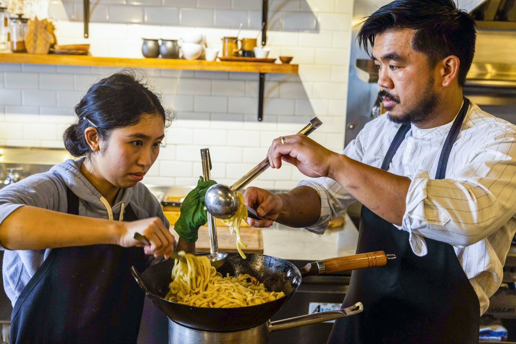 Ronnet Sanchez, left, and chef Aaron Verzosa prepare miki noodles at Archipelago. (Daniel Kim / The Seattle Times, archive photo)