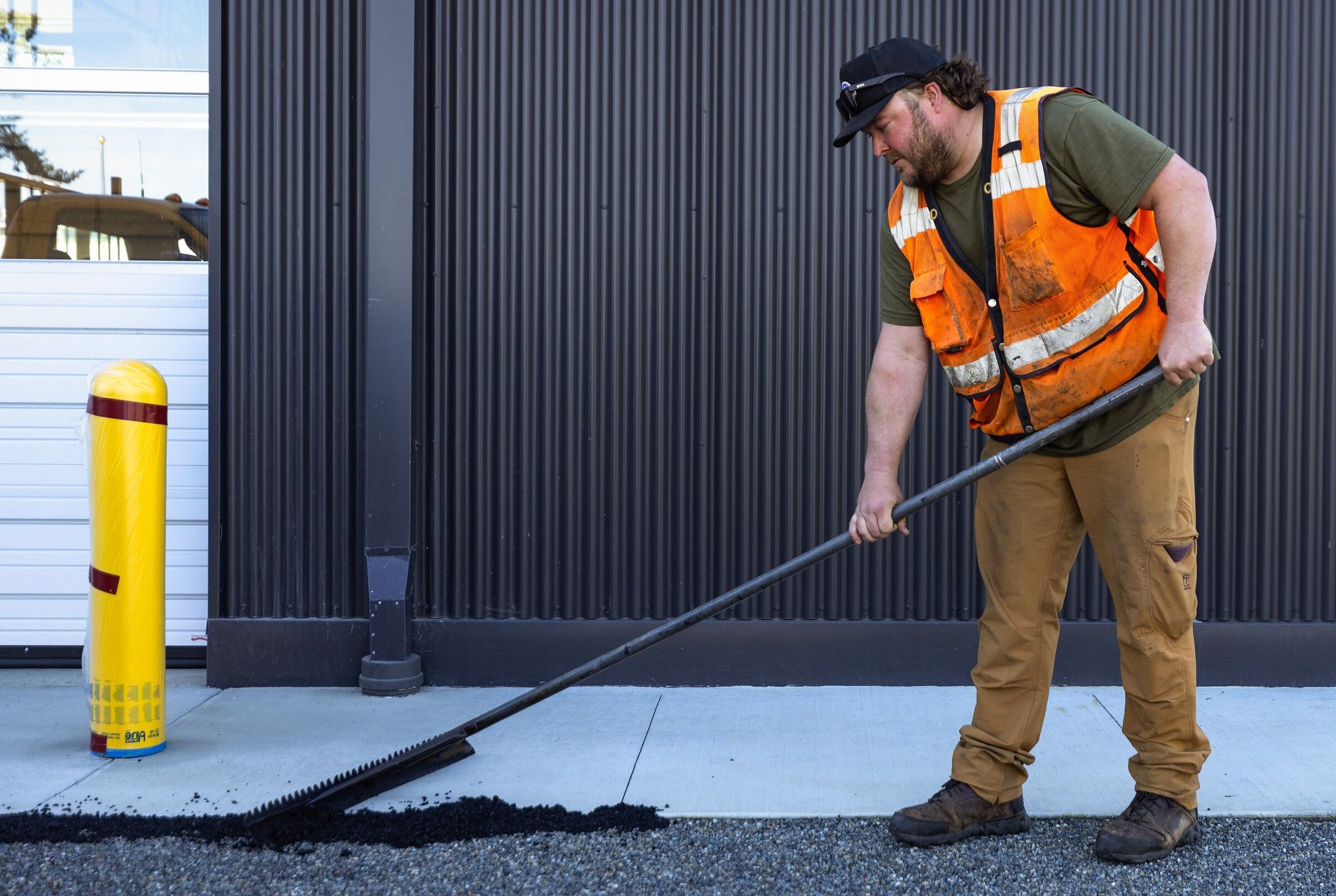 Brock Polda rakes gravel surfacing for San Juan County public works in May 2024, in Friday Harbor. (Nick Wagner / The Seattle Times)