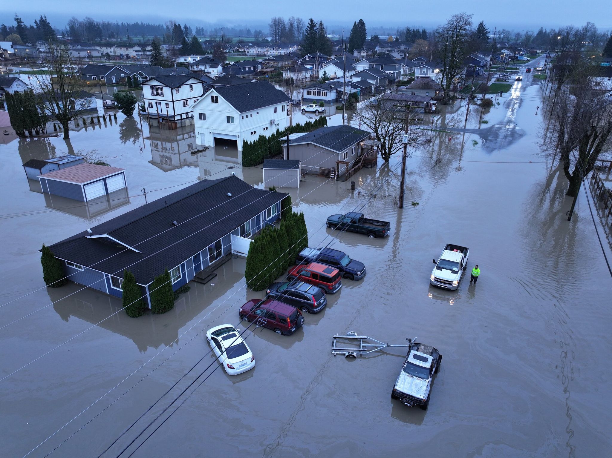 James Richardson talks with a worker who helped tow his truck home in Sumas, Whatcom County, last month. When it first stalled in floodwaters, he removed a boat from the trailer and used it to get home. (Karen Ducey / The Seattle Times)