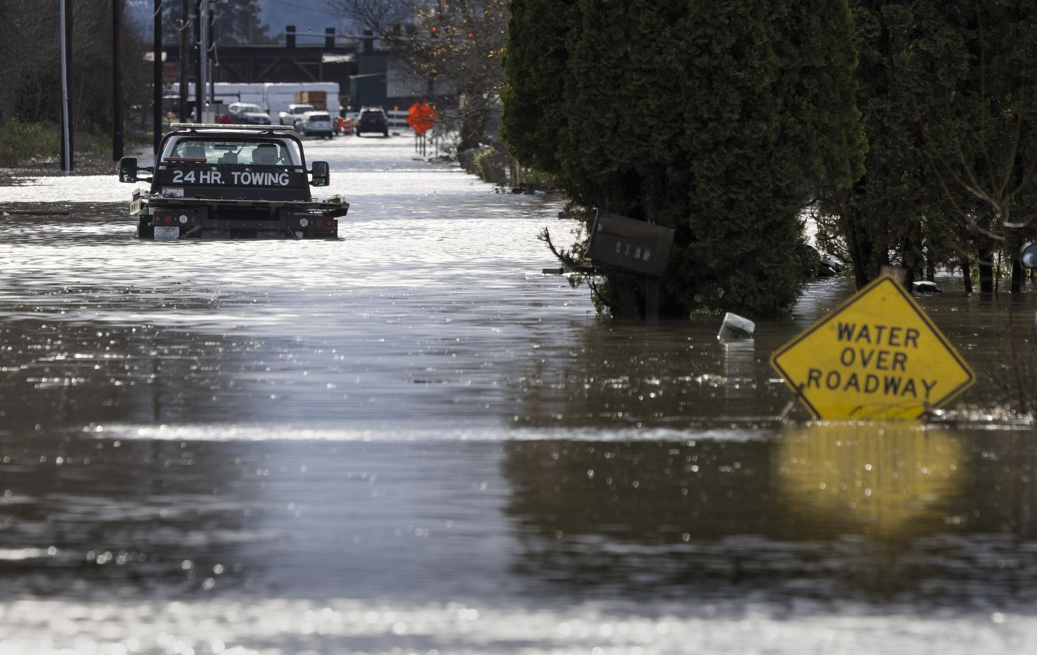 A tow truck drives on Butte Ave Southeast near County Line Road Southeast and becomes stuck in floodwaters spilling across the roadway at Pacific City Park last month. A section of temporary flood protection along Pacific breached and the White River inundated a large residential neighborhood in December. (Ellen M. Banner / The Seattle Times, 2025)