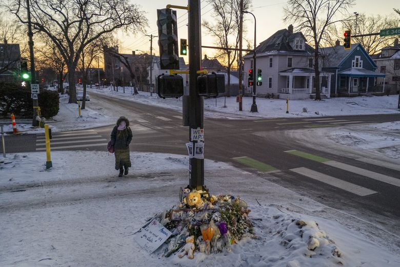 A woman walks through an intersection near items left by mourners at a makeshift memorial following the killing of Renee Good by an ICE agent in the neighborhood in Minneapolis, Jan. 20. (David Guttenfelder / The New York Times)