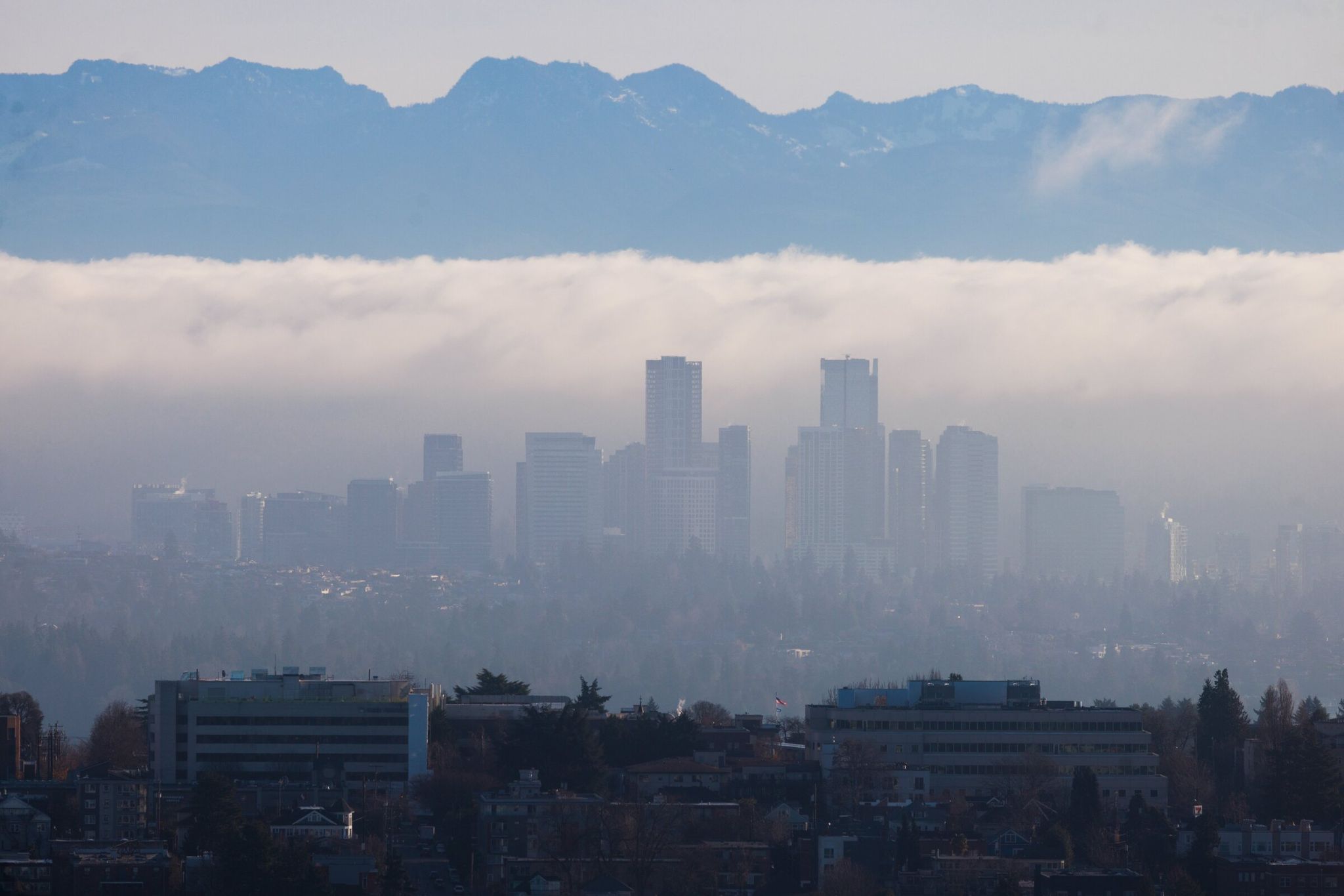 A panorama of Bellevue is visible through a layer of clouds with the Space Needle in the foreground this month. (Erika Schultz / The Seattle Times)