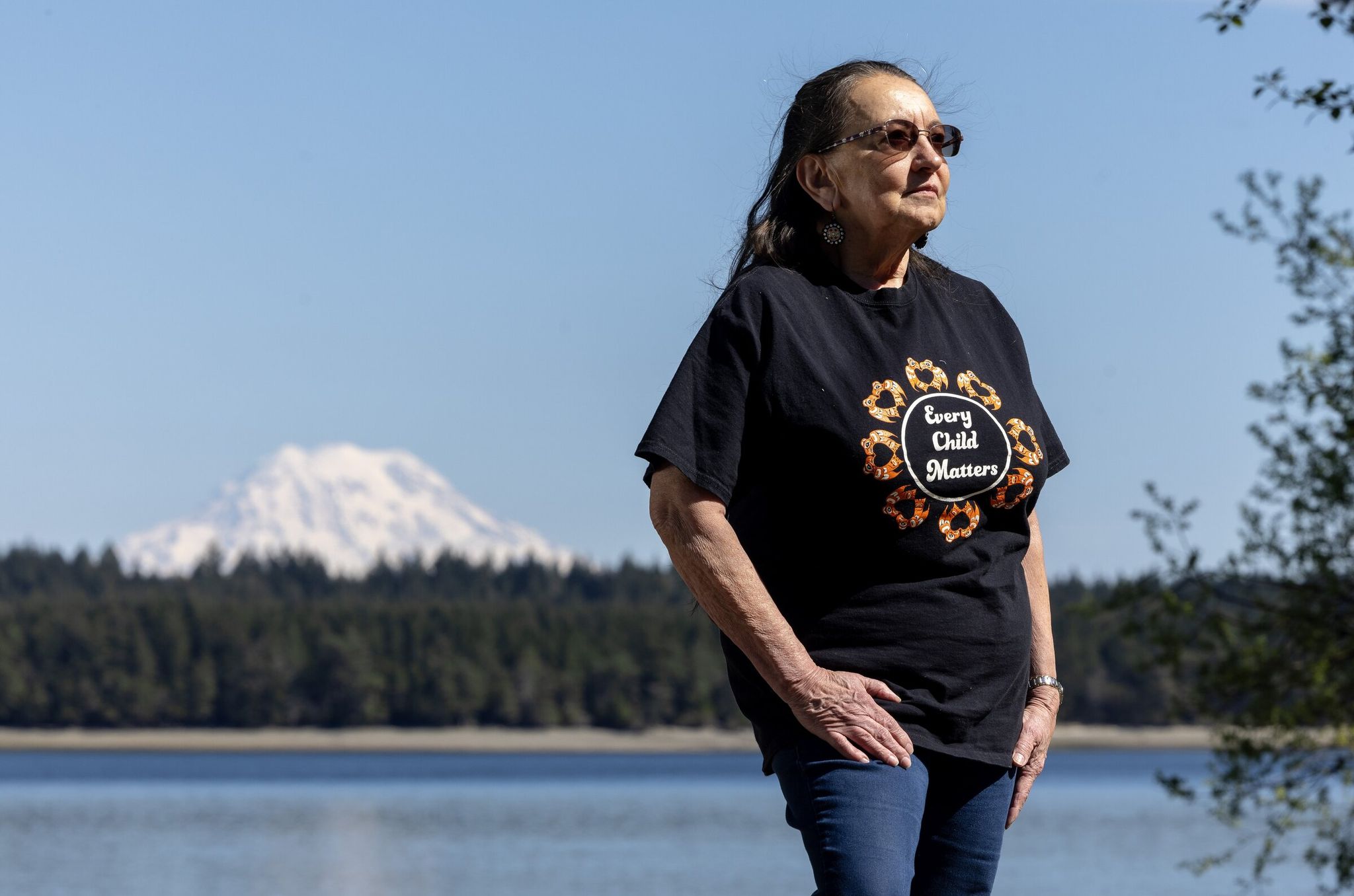 Sally Brownfield poses for a photo with Pickering Passage, Squaxin Island and Mount Rainier in the background, April 17, 2025, near Shelton, Mason County. (Nick Wagner / The Seattle Times)