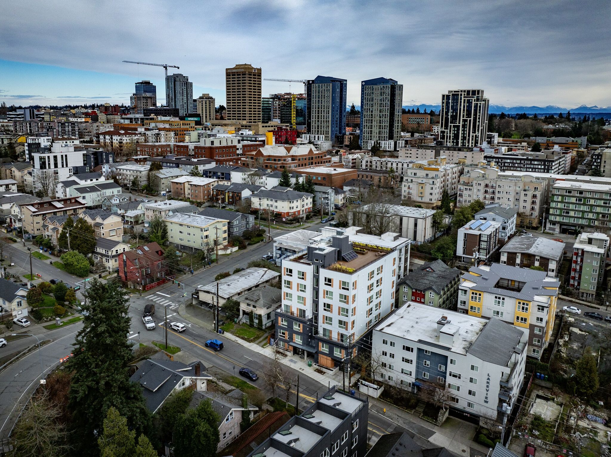 A cluster of multifamily buildings fills the foreground of the University District. If the Seattle City Council passes the housing bill, it would create more places where developers can build five- and six-story residential buildings. At that scale, city planners estimate, more projects will become economically feasible for builders while high-rise, eight‑to‑ten‑story construction would still be restricted. (Ken Lambert / The Seattle Times, 2024)