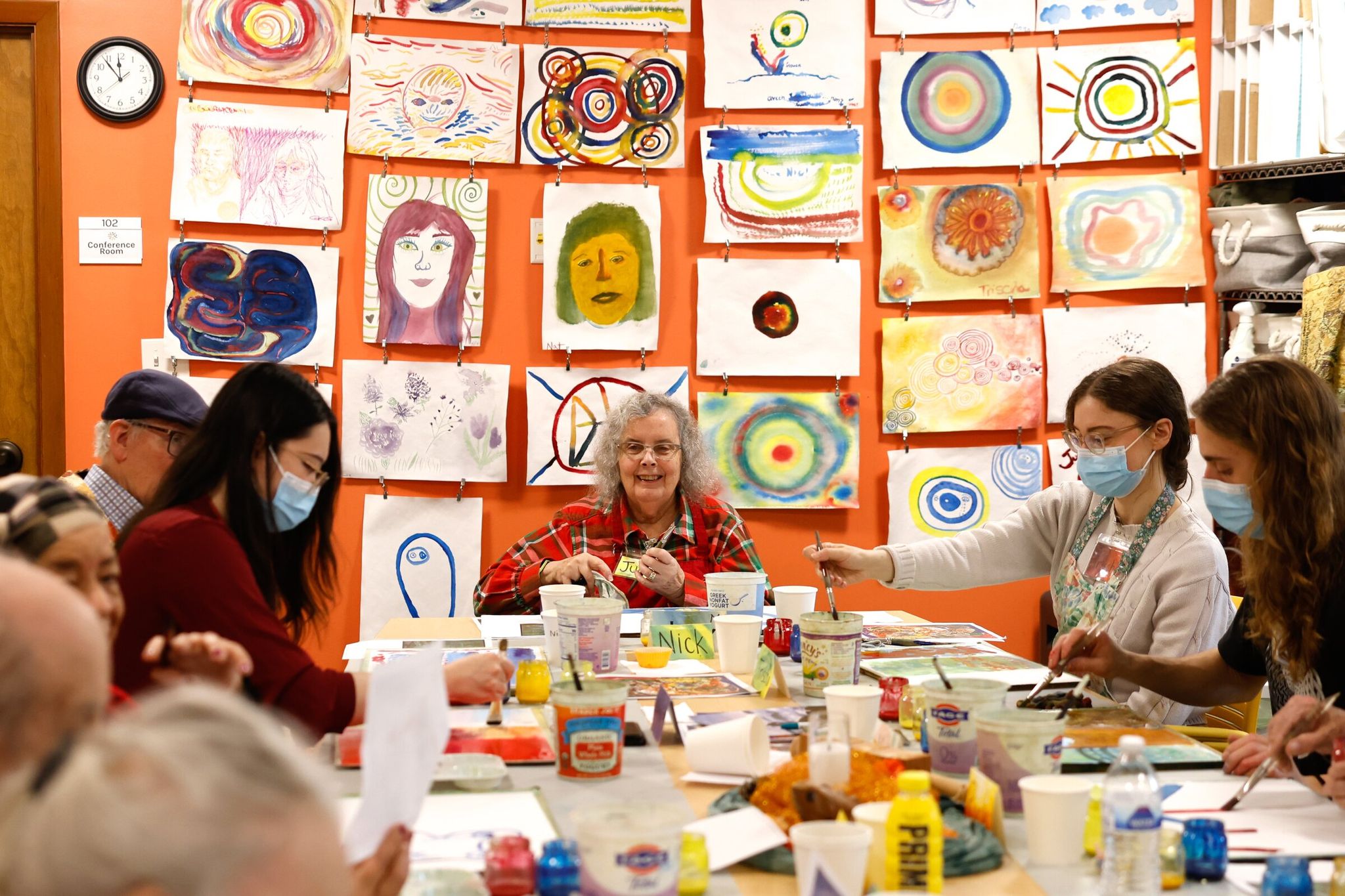 Judy Melissinos (center) sits with older adults experiencing memory problems and dementia and with their facilitators, who paint watercolors while listening to a live string quartet at the Memory Hub in Seattle last month. Sarah McKiddy, a doctoral student in the University of Washington’s nursing program, is studying the connection between music, brain health and dementia. (Karen Ducey / The Seattle Times)