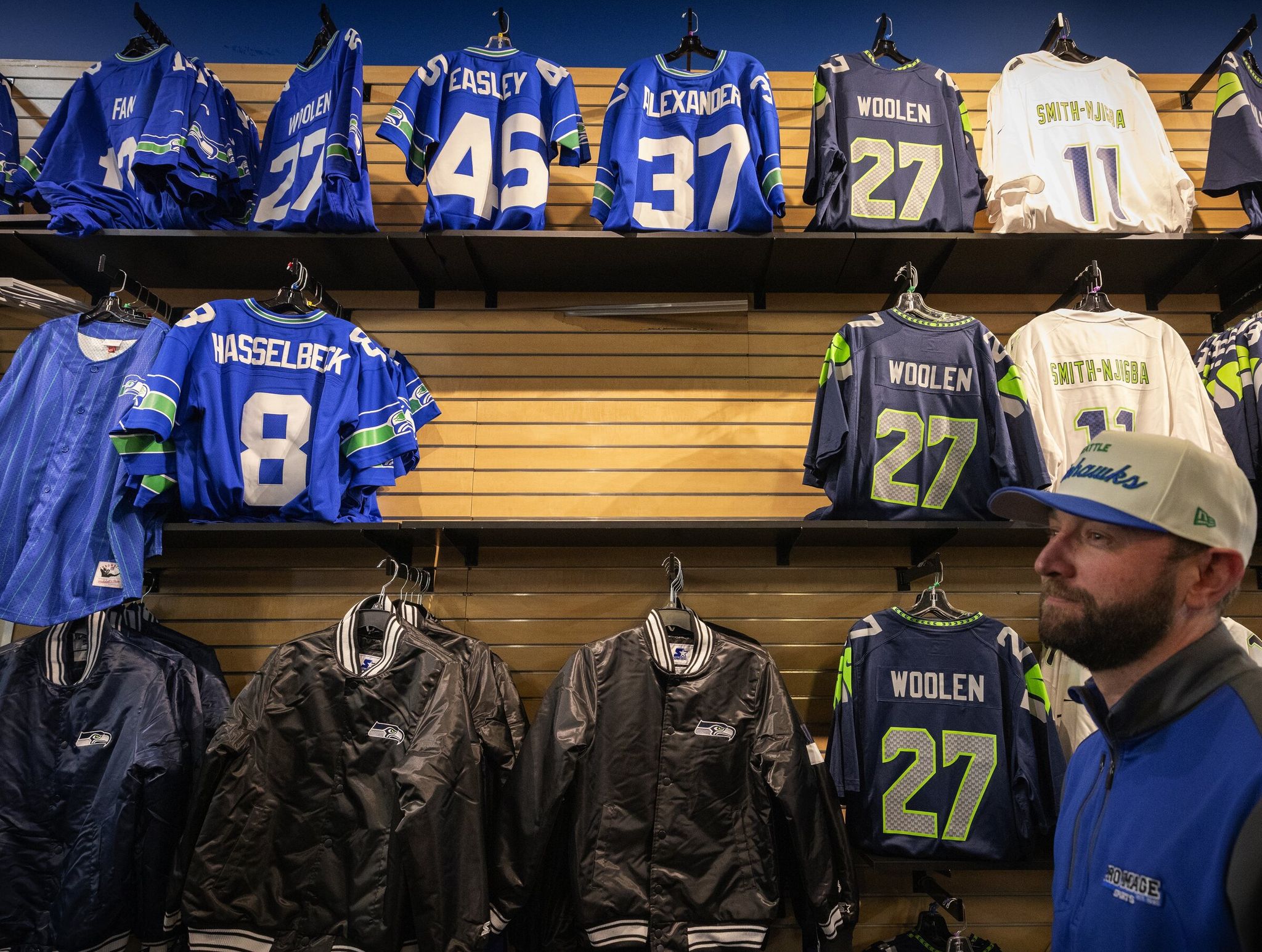 Clay Frongner, co‑owner of Pro Image Sports, shows the wall where thieves stole Seahawks merchandise Sunday in Seattle’s SODO neighborhood. Most of the display was restocked except for one damaged section. (Ken Lambert / The Seattle Times)