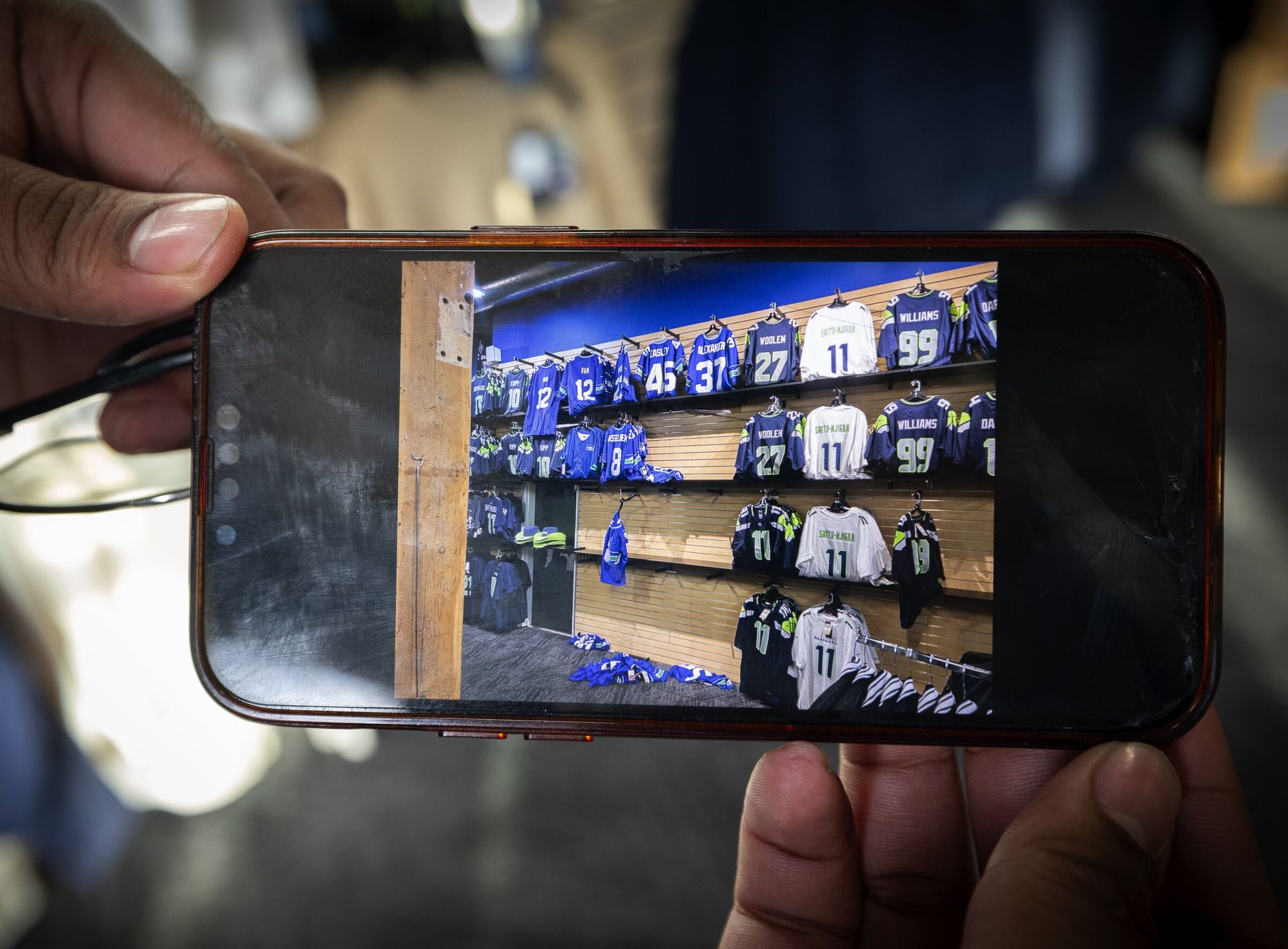 Tyres Trower, senior manager at Pro Image Sports, displays an image on his phone after thieves stole Seahawks merch early Sunday in Seattle’s SODO neighborhood. (Ken Lambert / The Seattle Times)