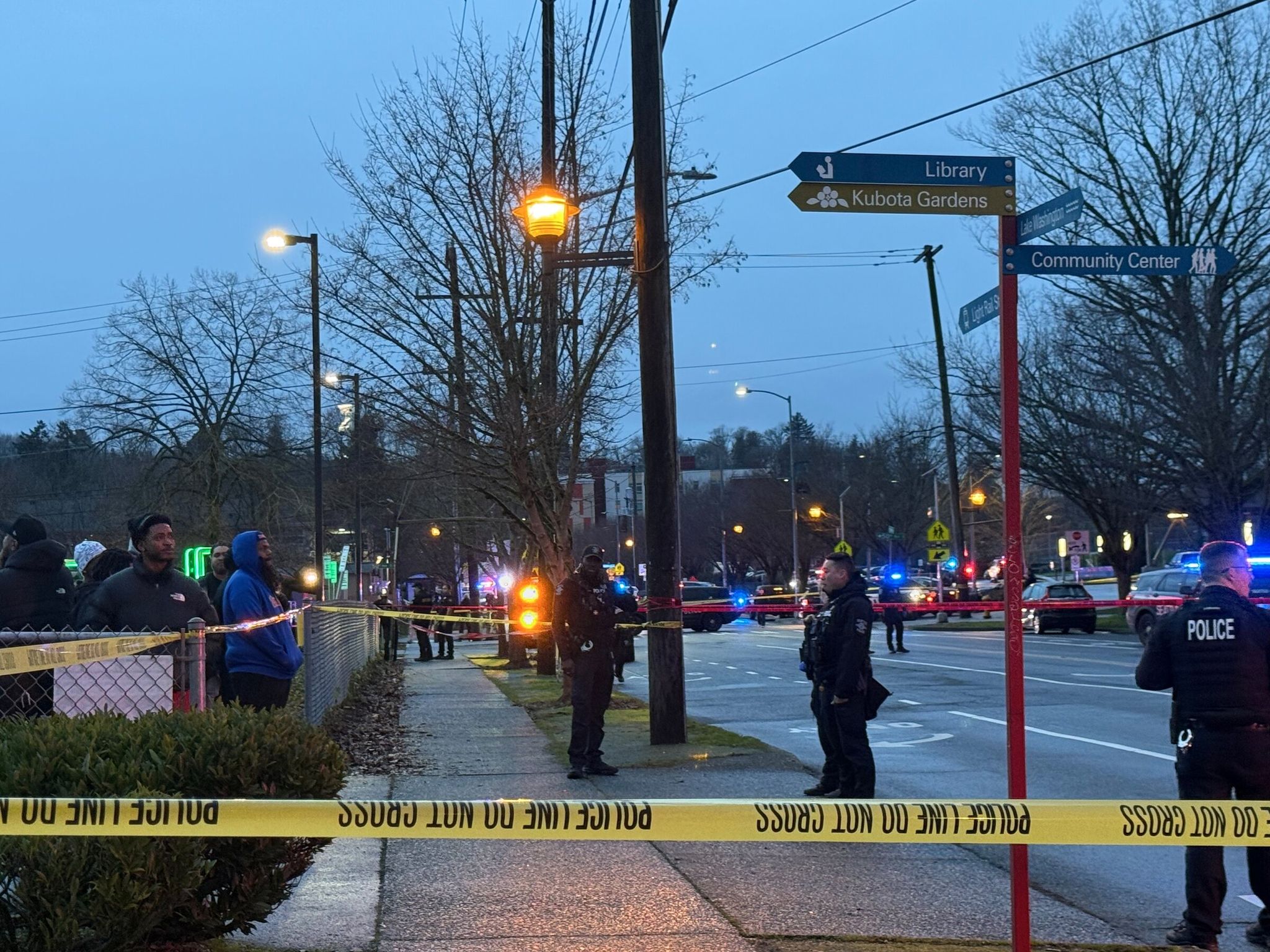 Police investigate the scene at the intersection of Rainier Avenue South and South Henderson Street on Friday, where, police say, two people were shot at a bus stop. (Ivy Ceballo / The Seattle Times)