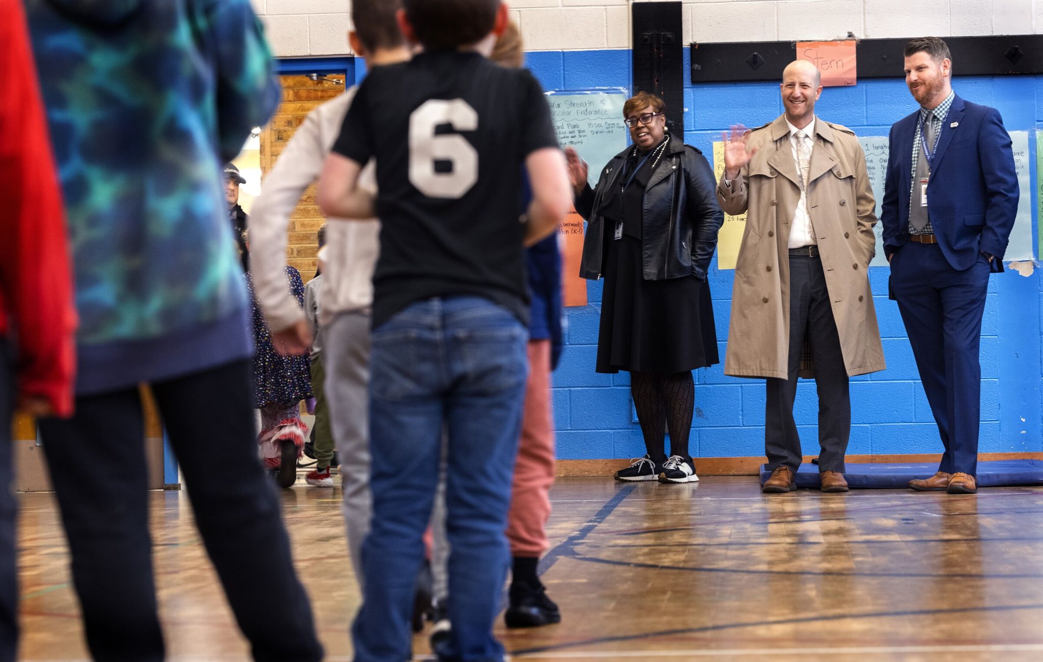 Seattle Public Schools Superintendent Ben Schuldtner, second from right, waves to students leaving the gym at Alki Elementary at Schmitz Park during a school tour with Principal Mason Skeffington, right, and others on Wednesday. To Schuldtner's left is Bev Redmond, SPS chief of staff. (Ellen M. Banner / The Seattle Times)