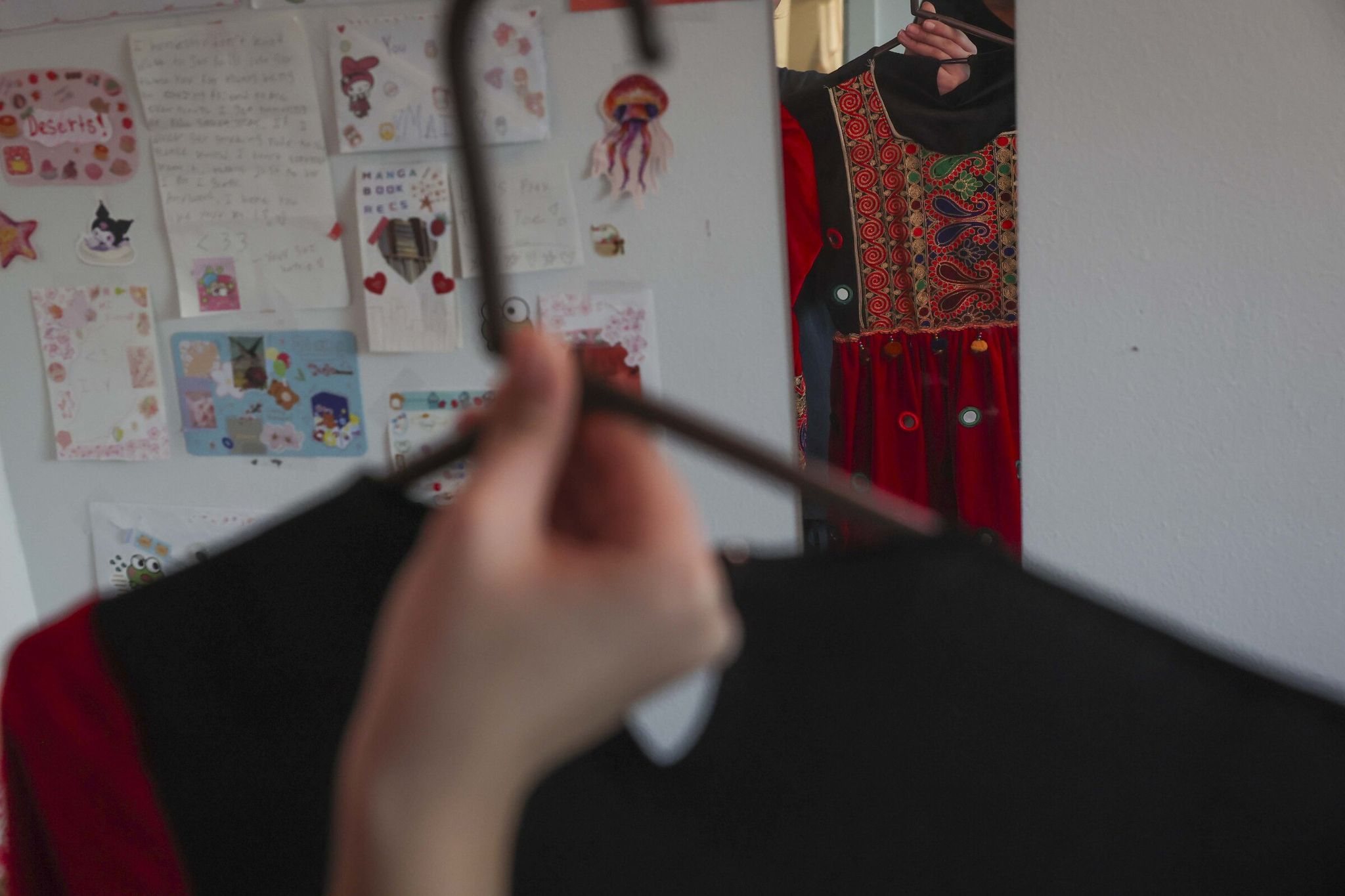 Sayed and Pari’s older daughter shows a traditional Afghan dress in her bedroom at her father's Seattle apartment last month. (Ivy Ceballo / The Seattle Times)