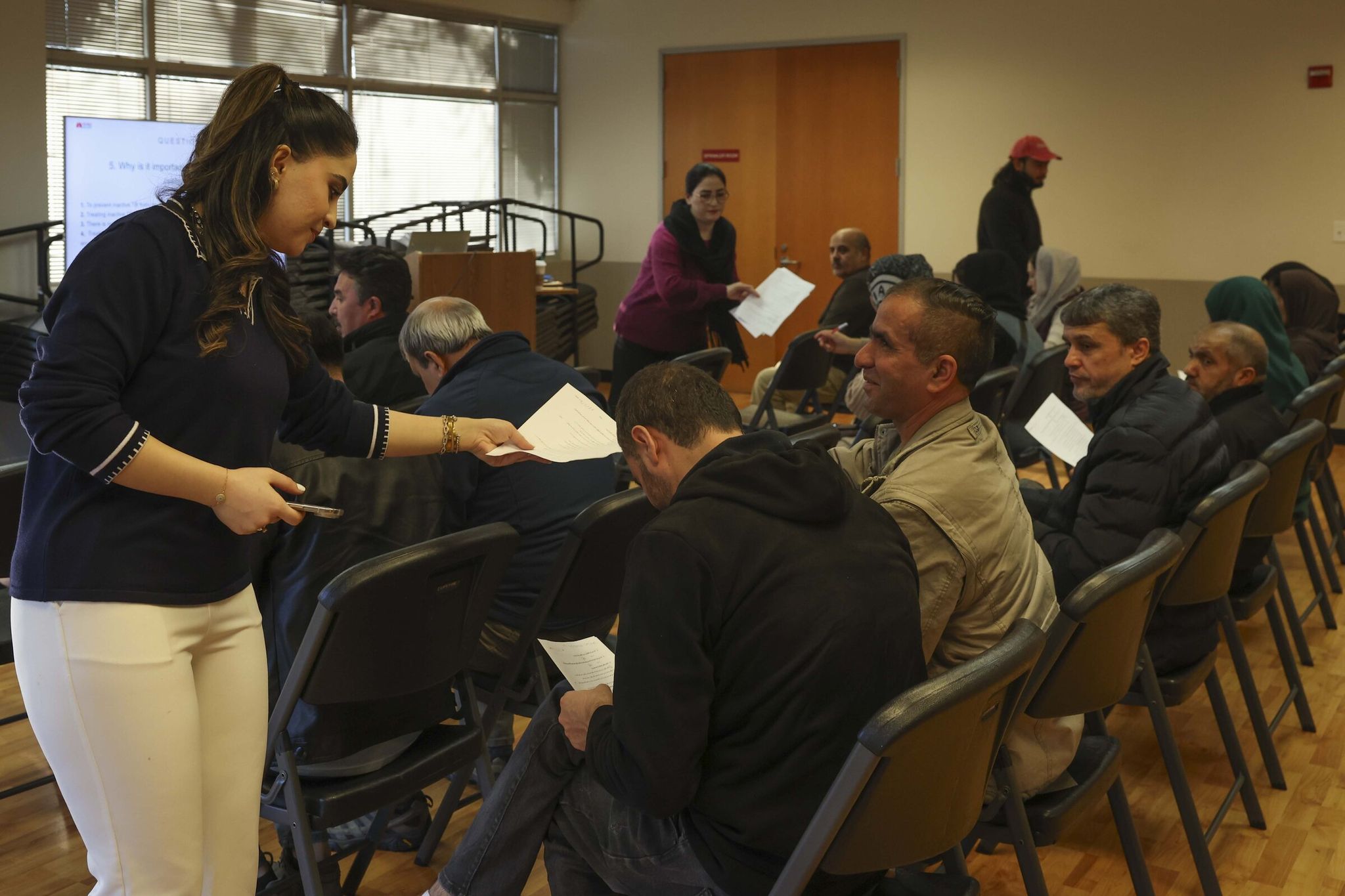 Zainab Aziz, left, who is an employment coordinator and client services manager at the nonprofit Afghan Health Initiative, assists participants on the last day of a job-search workshop at Covington City Hall last month. (Ivy Ceballo / The Seattle Times)