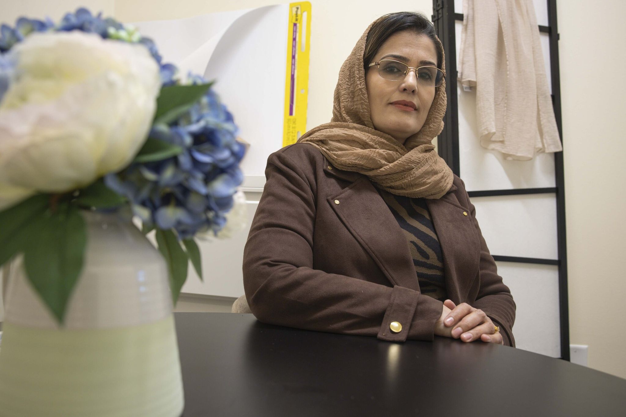 Gulmakai Azizi, who works as a family affairs coordinator at the Afghan Health Initiative, sits in a room and prays in the Afghan Health Initiative office at Covington City Hall. (Ivy Ceballo / The Seattle Times)