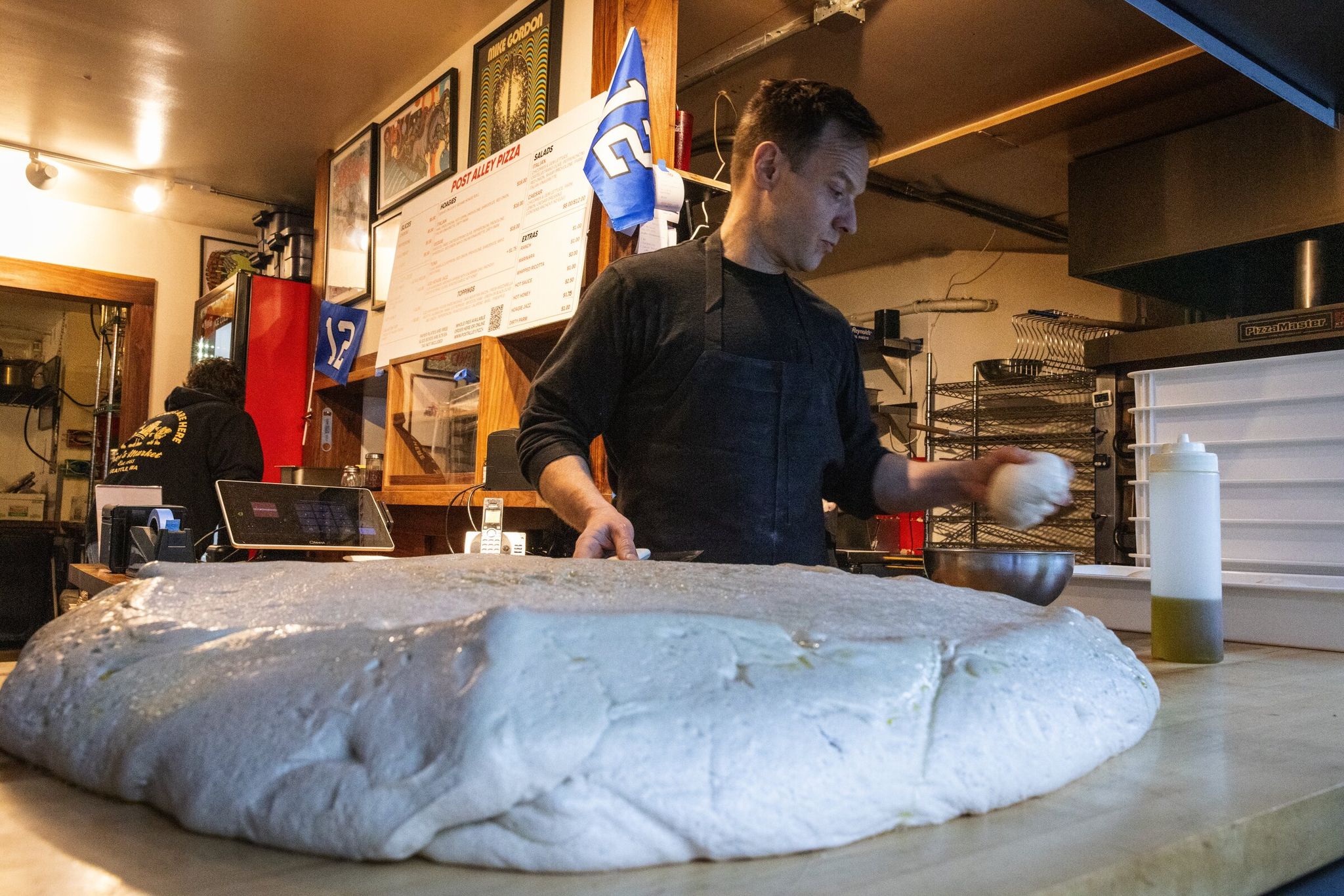 Andrew Gregory prepares pizza and sandwich dough at Post Alley Pizza on Wednesday. (Ken Lambert / The Seattle Times)