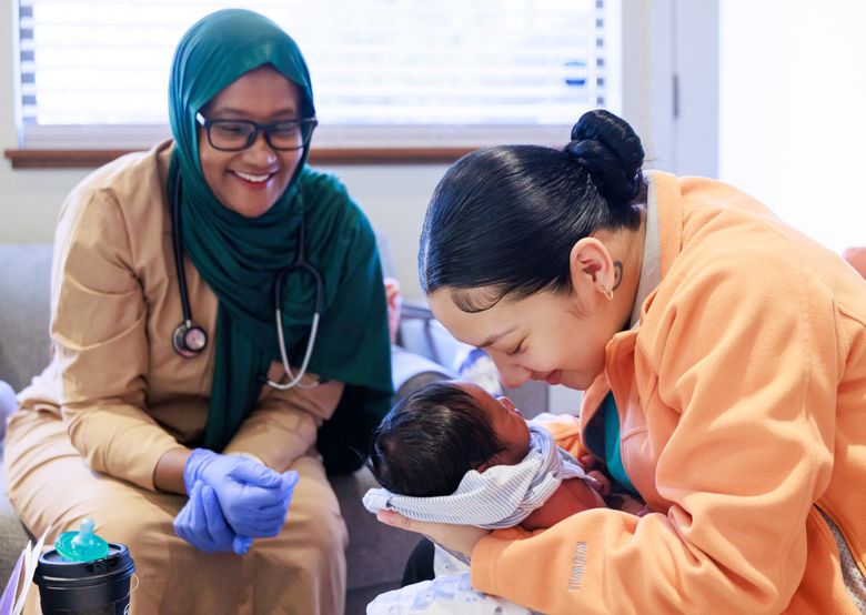 Licensed midwife Faisa Farole, left, talks with Amelia Carmona and her son Honour, 12 days old, during an appointment at the Federal Way Birth Center, which opened in 2023 to improve health outcomes among Black and brown families. “Birth is a ceremony,” Carmona said. “These are the most vital parts of the baby’s life, the first year, the first few months, the first few weeks.” Carmona said Farole and her doula worked together to support her before, during and after birth — and set her family up for success. “Support is love,” Carmona, said. “Support for someone’s family, for my kids, for my newborn, for myself, my partner, all of us as a whole.” Carmona said the love of her new child is also “the purest form of love, something that you made and created and is a gift from God.”
(Erika Schultz / The Seattle Times)