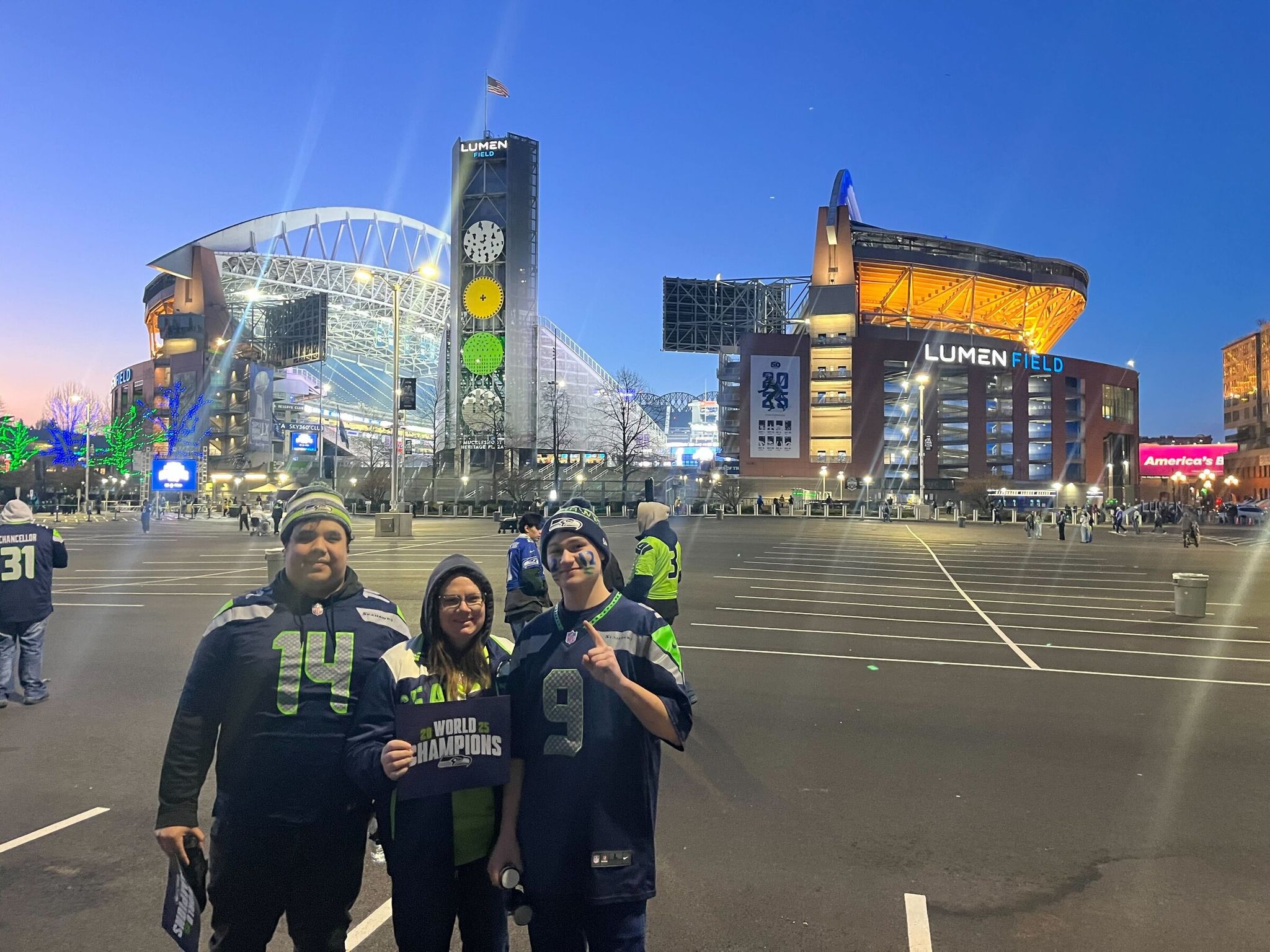 Andrew Woods, right, was on the first Sound Transit Sounder train that departed Sumner at about 5 a.m. He was in the parking lot with his mom, center, and a friend before sunrise over Lumen Field. (Kai Uyehara / The Seattle Times)