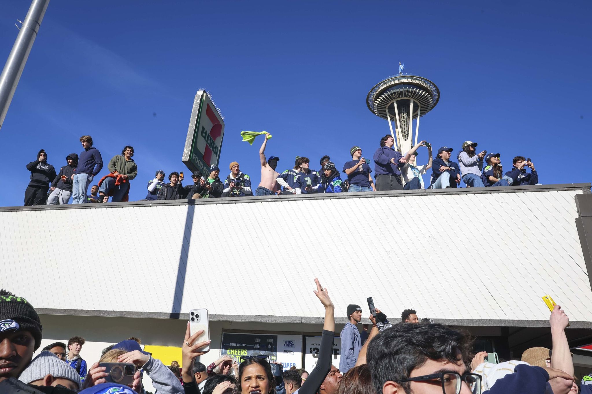 Seattle Seahawks fans wait to see the Super Bowl champions on the roof of a 7-Eleven along Denny Way during the Seahawks' Super Bowl LX parade in Seattle on Wednesday, Feb. 11, 2026. (Ivy Seballo / The Seattle Times)