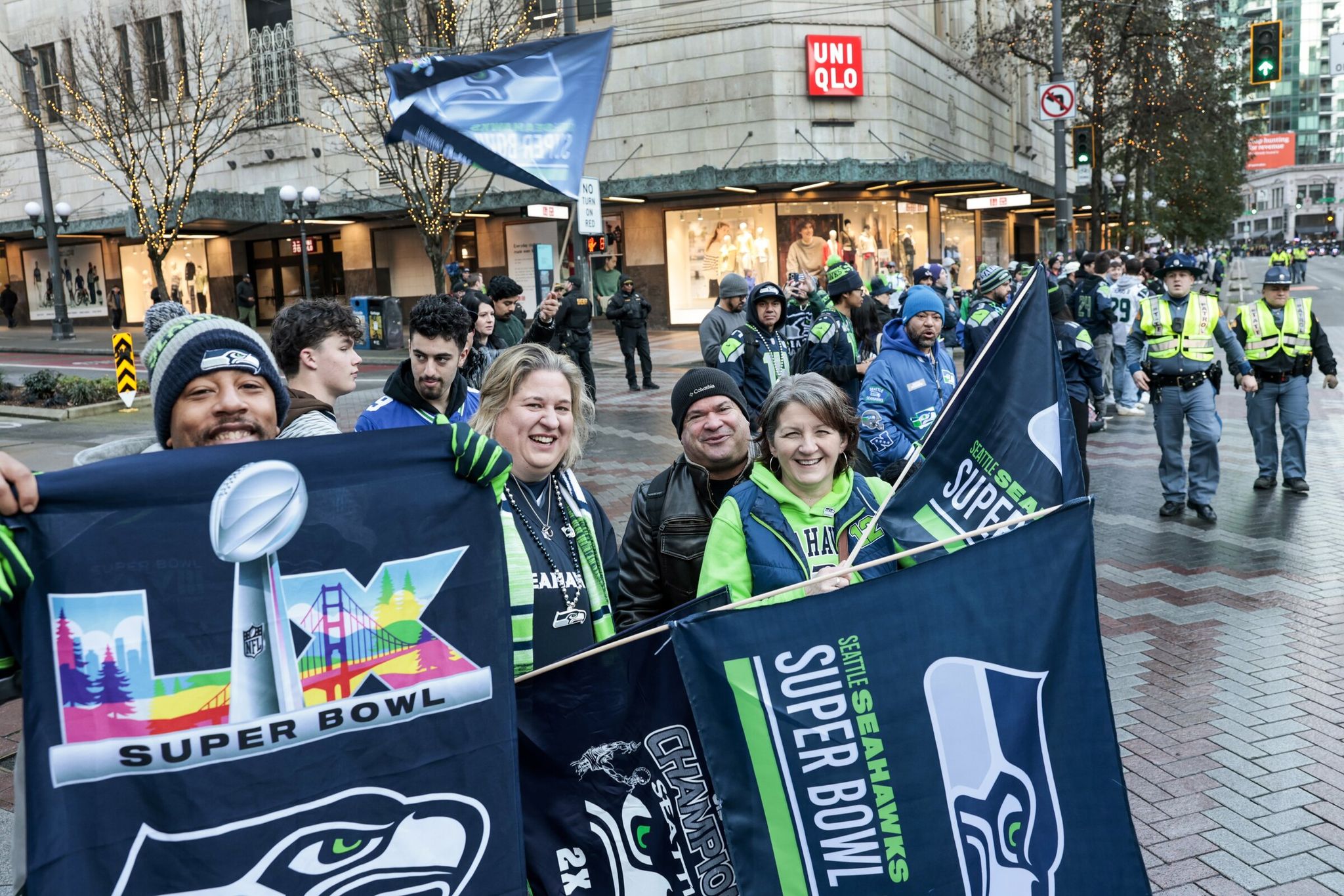 Left to right, holding flags: Walt James of Seattle, Tia Smart of Port Orchard, Joe and Kim Morales of Tacoma wait for the parade to begin. They arrived at 5:40 a.m. Fans line Fourth Avenue during the Seahawks world champions parade in Seattle on Wednesday. (Karen Ducey / The Seattle Times)