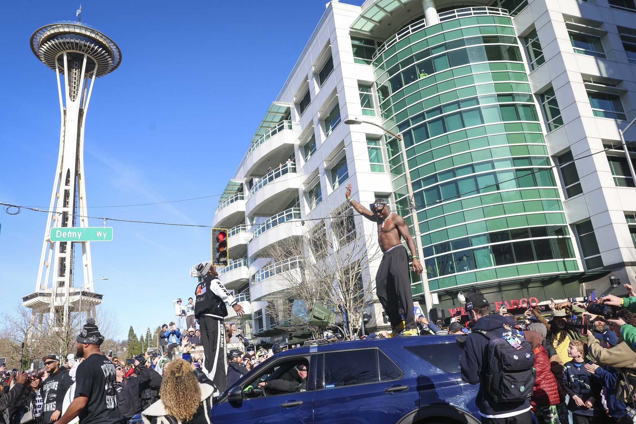 Seahawks defensive end DeMarcus Lawrence interacts with fans on the roof of a vehicle during the Seahawks championship parade — Super Bowl LX 2026 celebration on Denny Way in Seattle on Wednesday. (Ivy Seballo / The Seattle Times)
