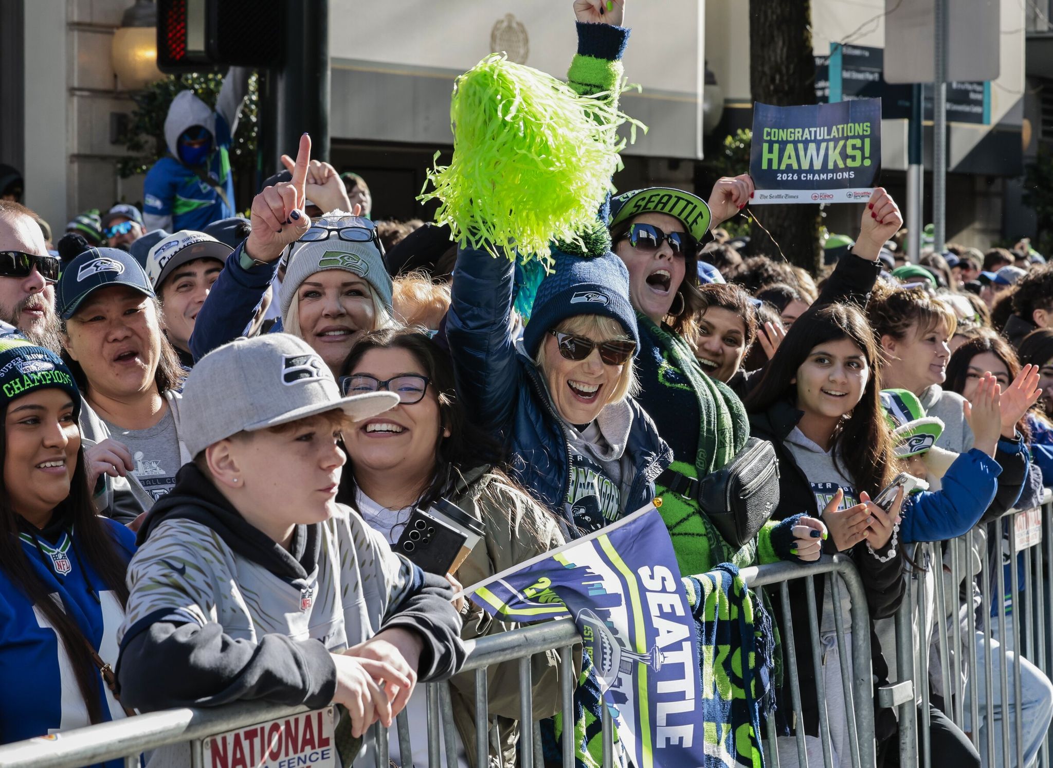 Debbie Tott (with a green pom), from Kenmore, and Monica Davis, from Federal Way (behind her, in a baseball cap), wait with other fans on Fourth Avenue for the start of the Seahawks world champions parade in Seattle on Wednesday. (Karen Ducey / The Seattle Times)