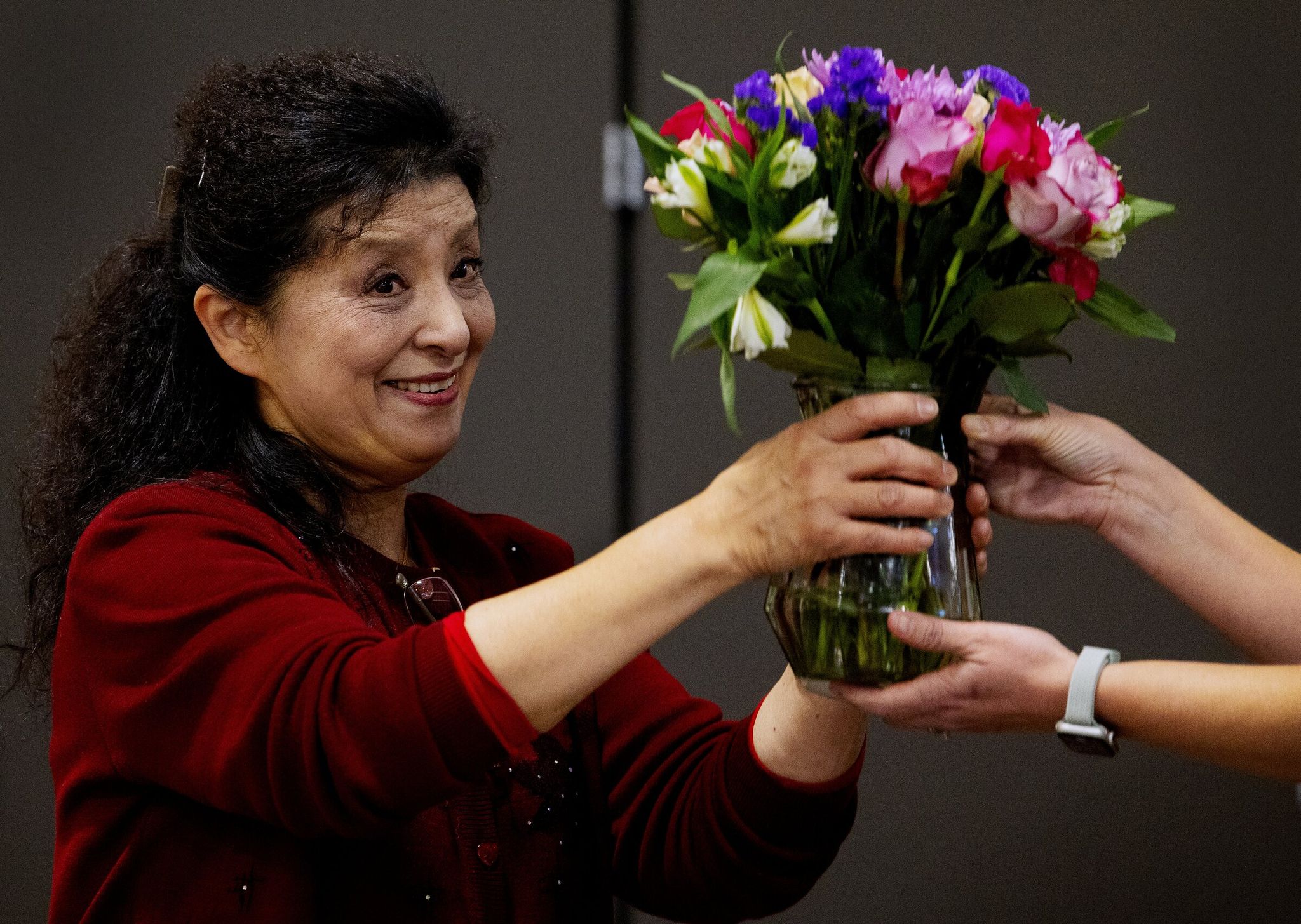 Helen Zhou, who has taught music and dance in Seattle public schools and coordinates the Lunar New Year celebration at Dearborn Park International Elementary — which tours other schools — receives flowers at the end of the school show. (Ken Lambert / The Seattle Times)