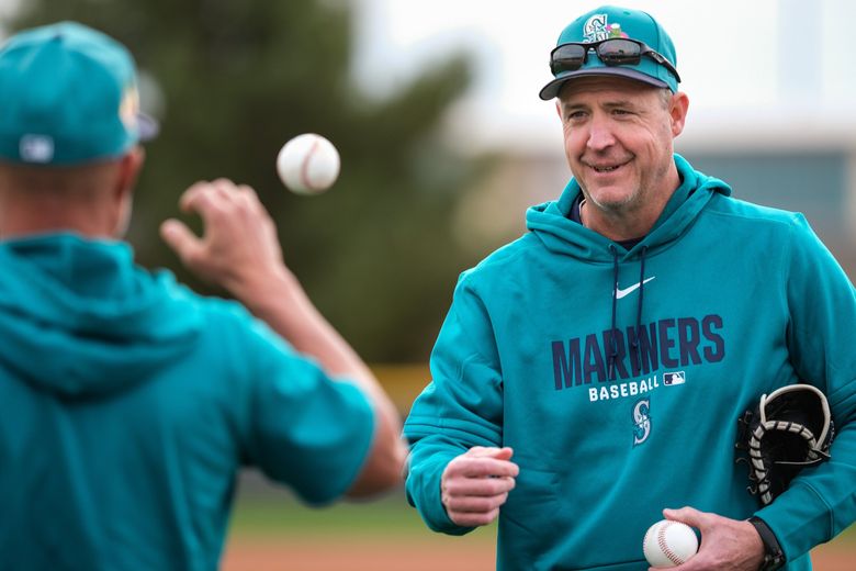 Manager Dan Wilson tosses balls to coach Manny Acta during infield drills Monday at Spring Training in Peoria, Ariz. (Dean Rutz / The Seattle Times)