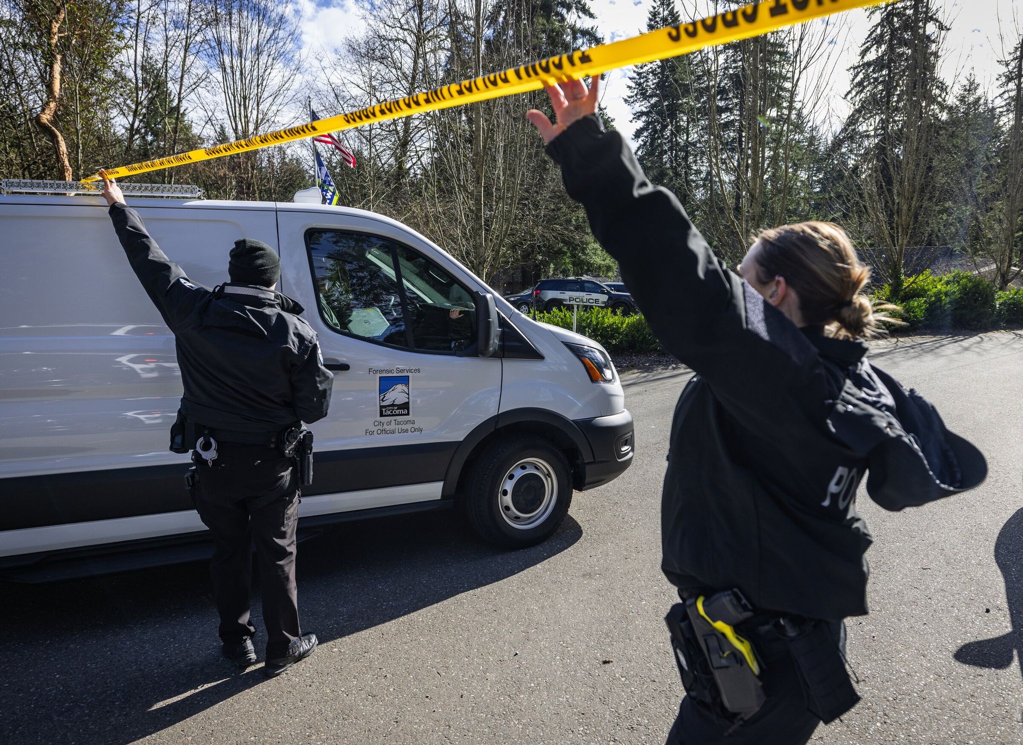 Law enforcement personnel allow a Tacoma crime scene unit vehicle to pass at a Pierce County crime scene on Tuesday. Police say they shot a man who fatally stabbed four people in this Key Peninsula incident near Gig Harbor. (Ken Lambert / The Seattle Times)