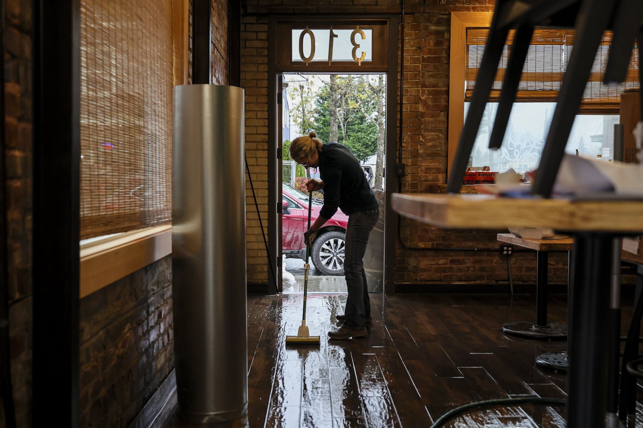 Molly Moss mops the floors at Harvest Kitchen after floodwaters receded in Sultan in December. (Kevin Clark / The Seattle Times)