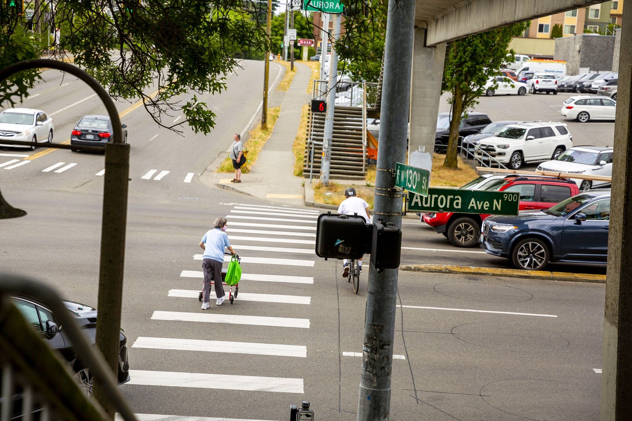 Pedestrians cross the street on 130th St. and Aurora Ave., in North Seattle. (Sylvia Jarrus / The Seattle Times, 2021)