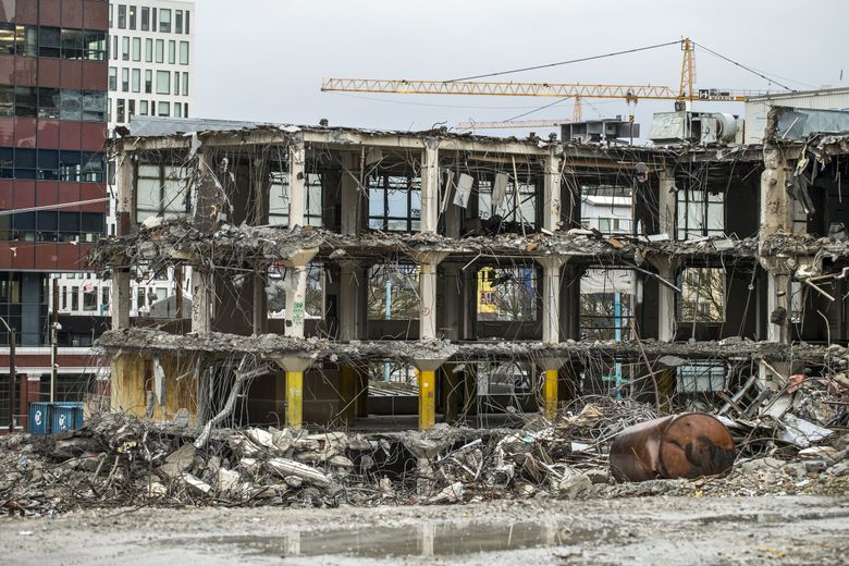 The old Seattle Times building at Fairview and John Street is seen in a state of demolition in 2017 with new South Lake Union buildings rising beyond. Only the 1931 facade, with Seattle landmark status, survives. (Bettina Hansen / The Seattle Times, 2017)