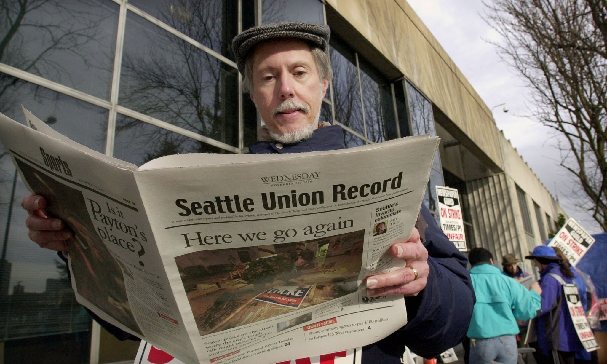 Seattle Times page designer and striker Dave Feltus reads the final issue of the Seattle Union Record, the paper produced by striking journalists, while standing on a 2000 picket line. (Elaine Thompson / The Associated Press)