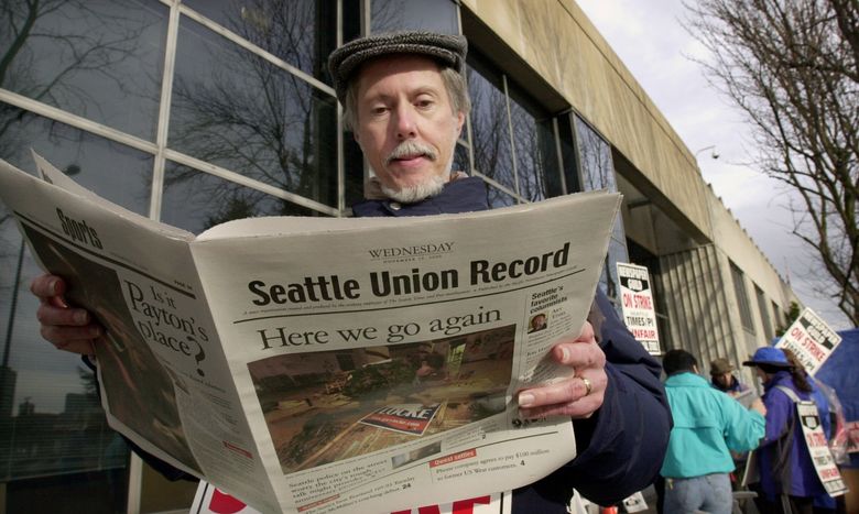 Striking Seattle Times page designer Dave Felthous reads the latest edition of the Seattle Union Record, a paper produced by striking journalists, as he stands on the picket line in 2000. (Elaine Thompson /The Associated Press)