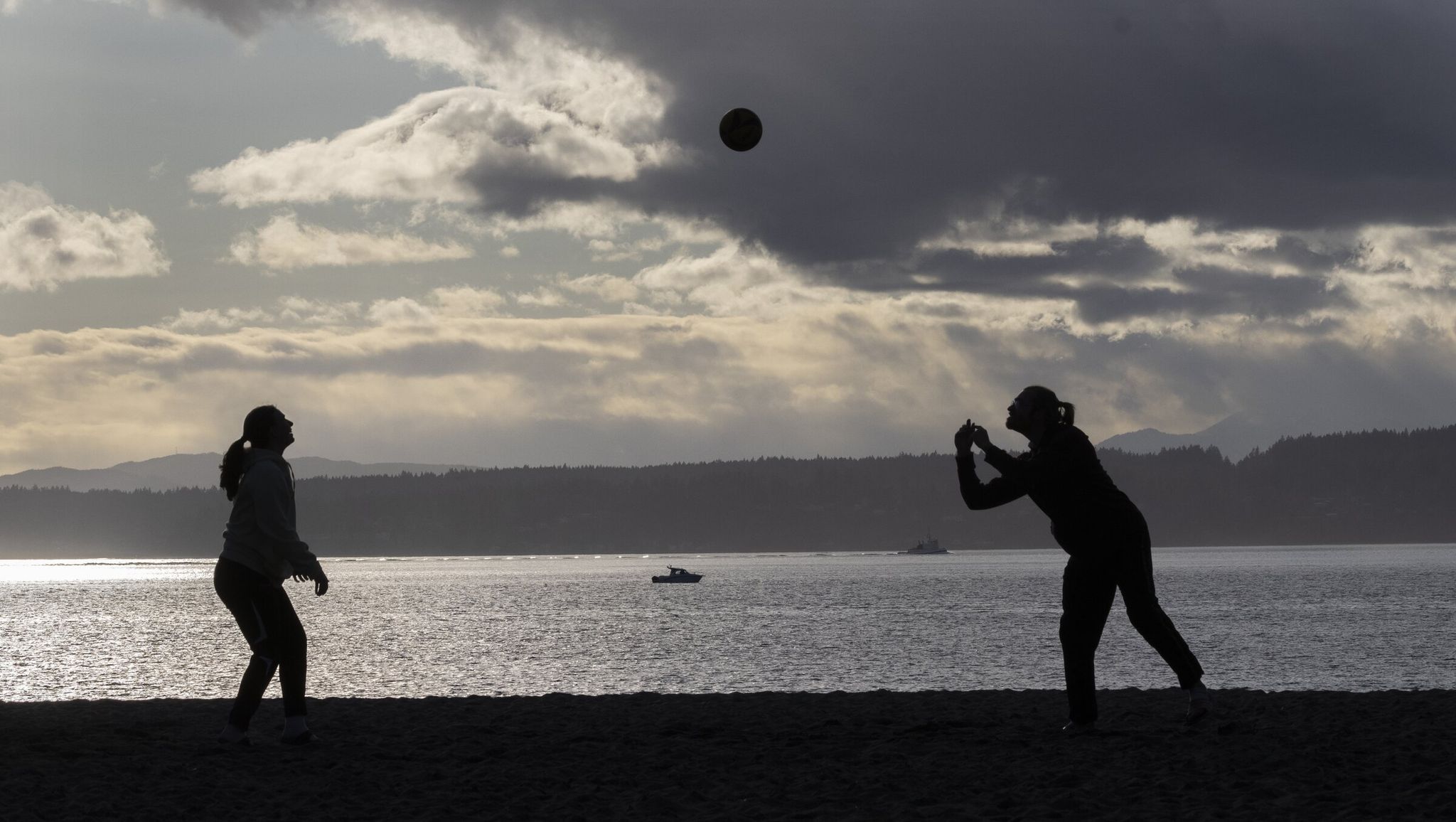 Marybeth Ohanlon, left, and Austin Bryan play volleyball late in the day last week at Golden Gardens Park. (Ellen M. Banner / The Seattle Times)