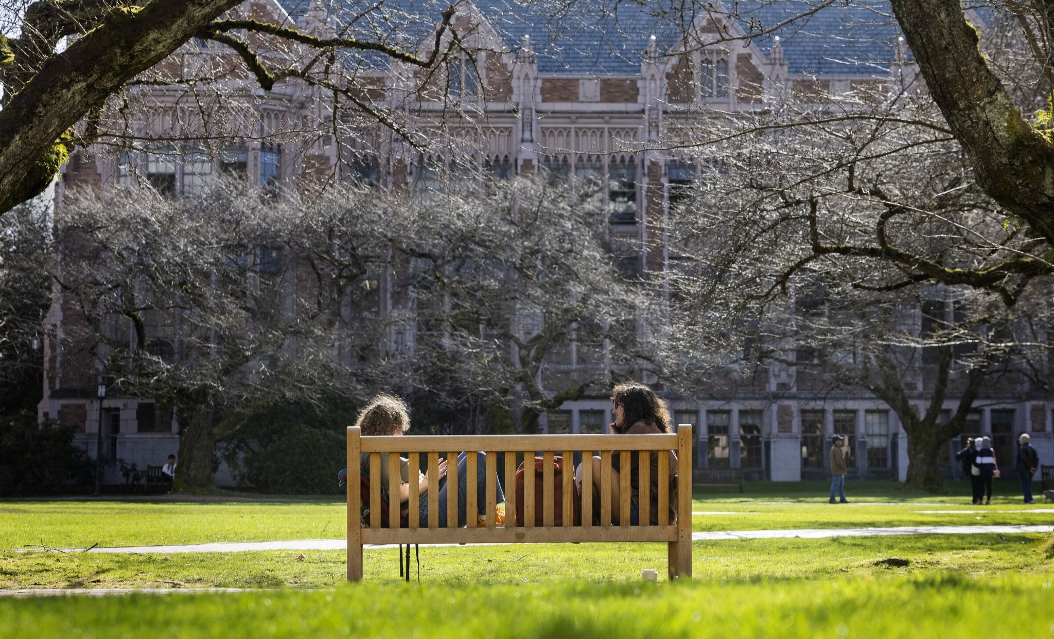 Сидни Мендельсон (слева) и Адая Стюарт, обе — третьекурсницы Университета Вашингтона, наслаждаются солнцем, отдыхая в Квад на кампусе 5 марта 2025 года. (Эллен М. Бэннер / The Seattle Times)